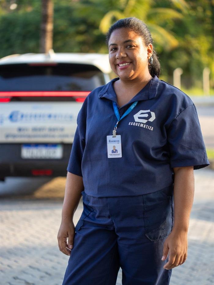 Colaboradora da Esquematiza uniformizada, sorrindo, em local de operação.